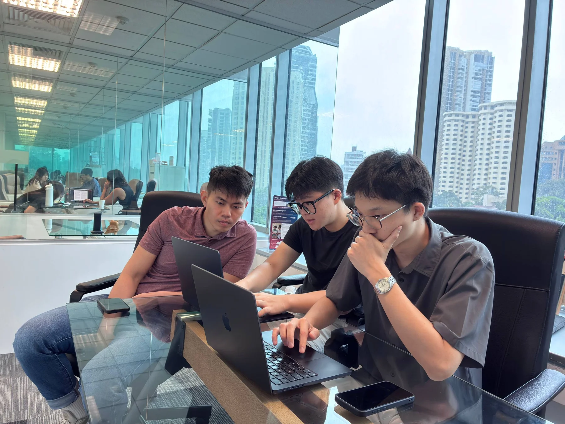 A mentor and two students working through a project on laptops